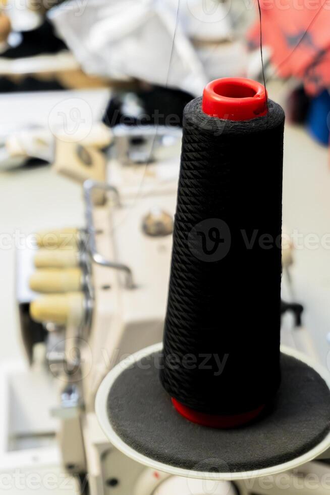 Black thread spool on a sewing machine in a bright workshop photo