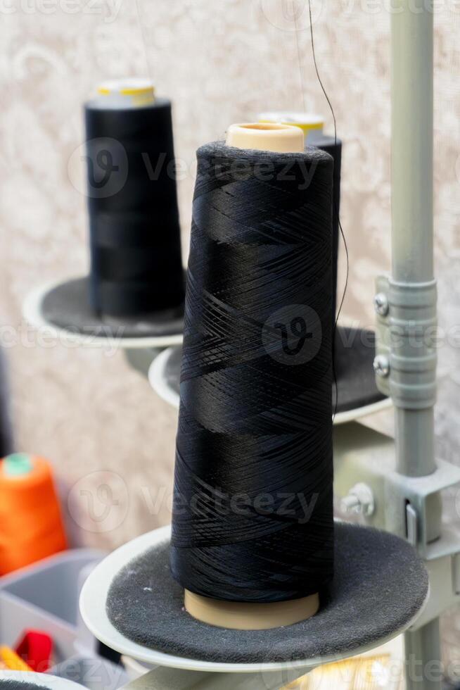 Spools of black thread on a sewing machine in a textile workshop photo