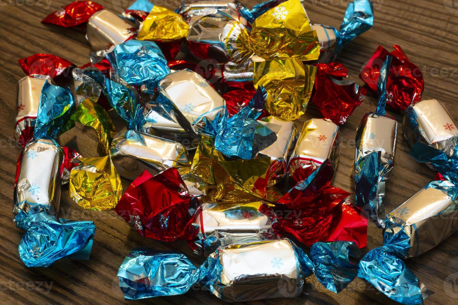 Colorful wrapped candies scattered on a wooden table in bright light photo
