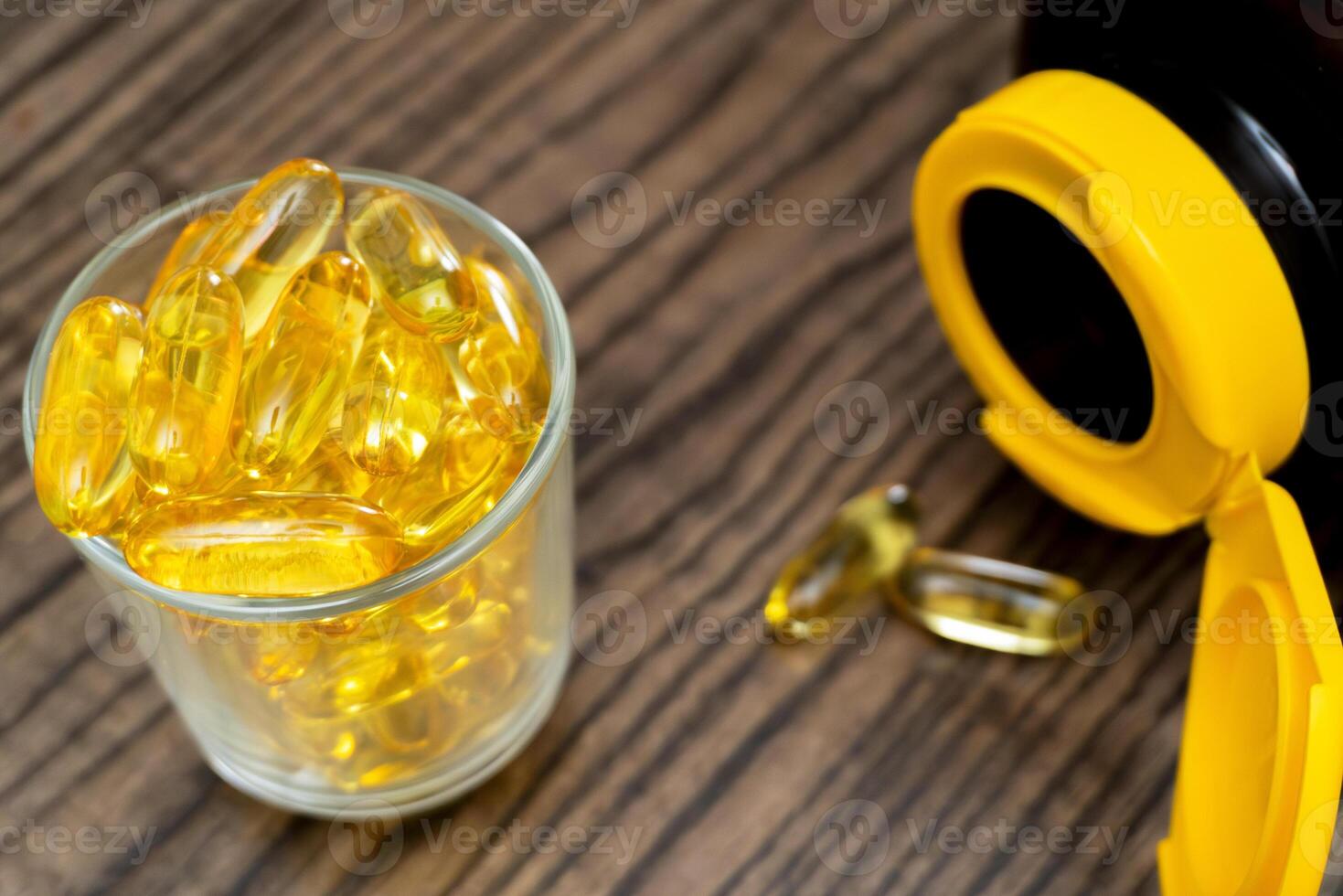 Health supplements in a glass on a wooden table with a container nearby photo