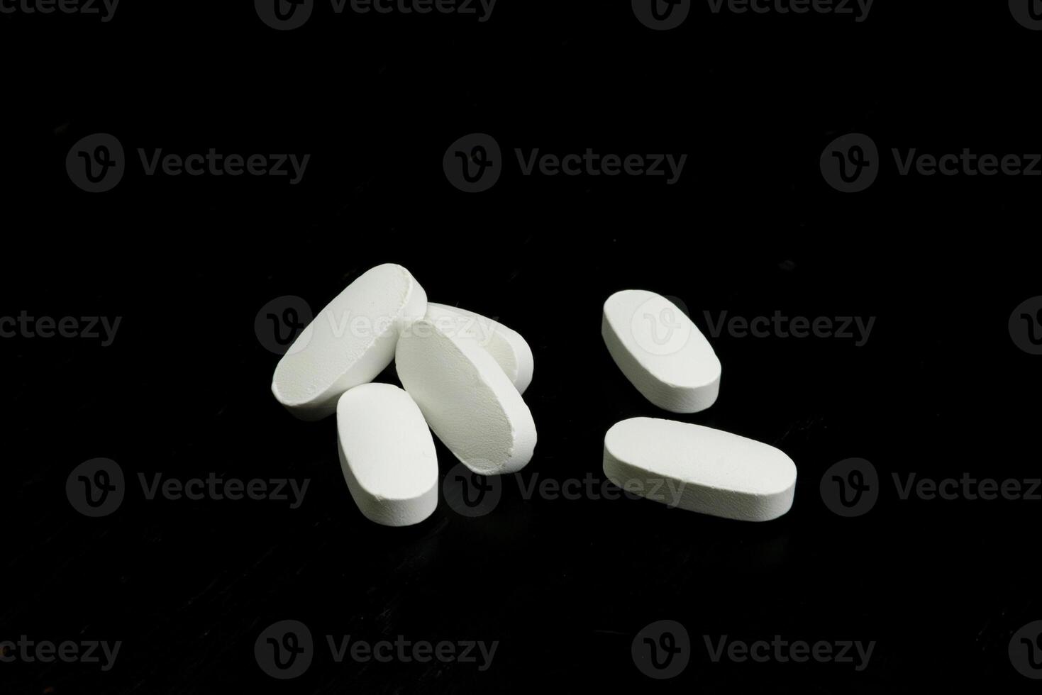 White tablets scattered on a black surface showcasing medical products photo