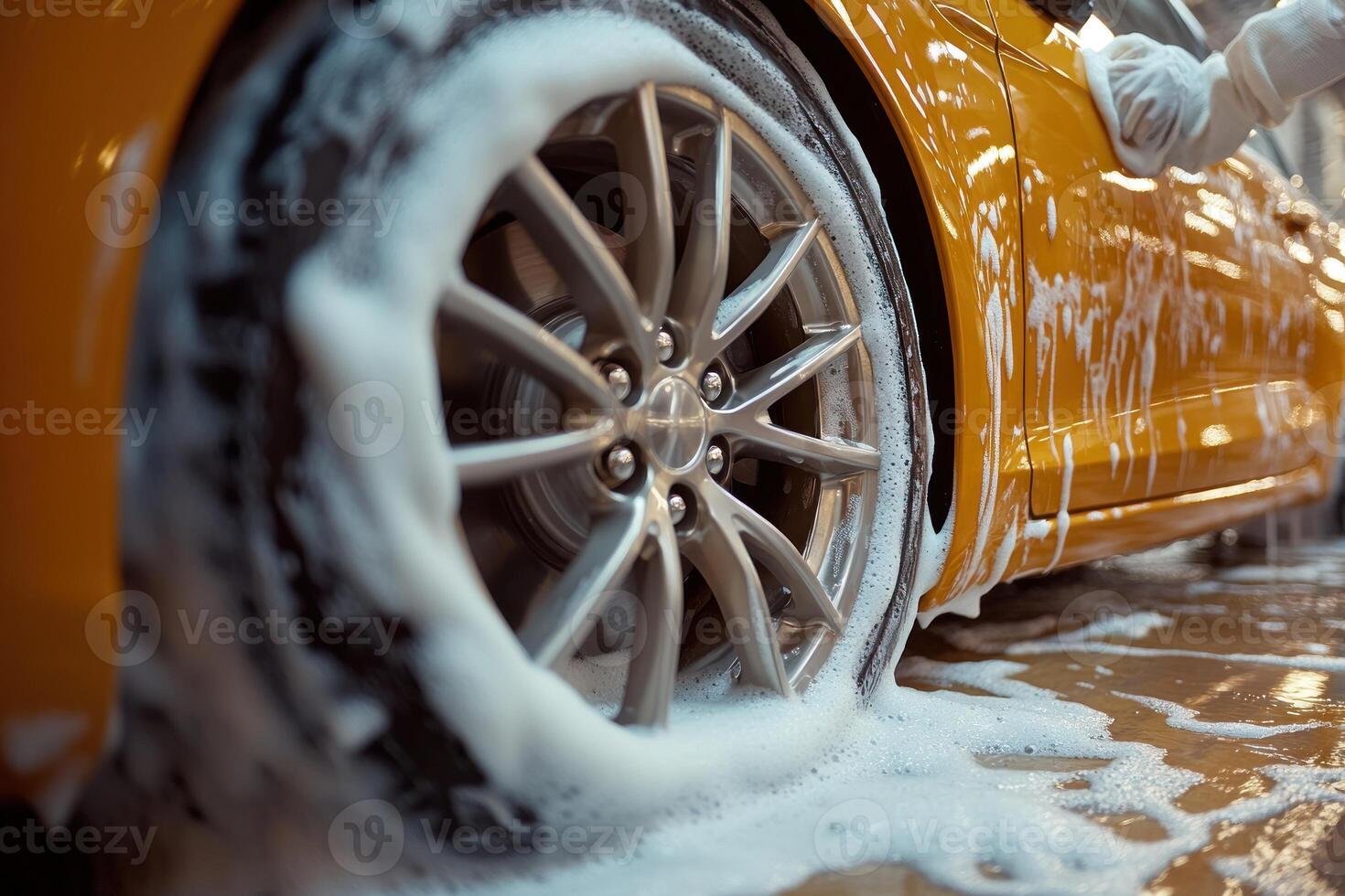 A bright yellow car gleams while getting thoroughly cleaned with soap and water in a car wash photo