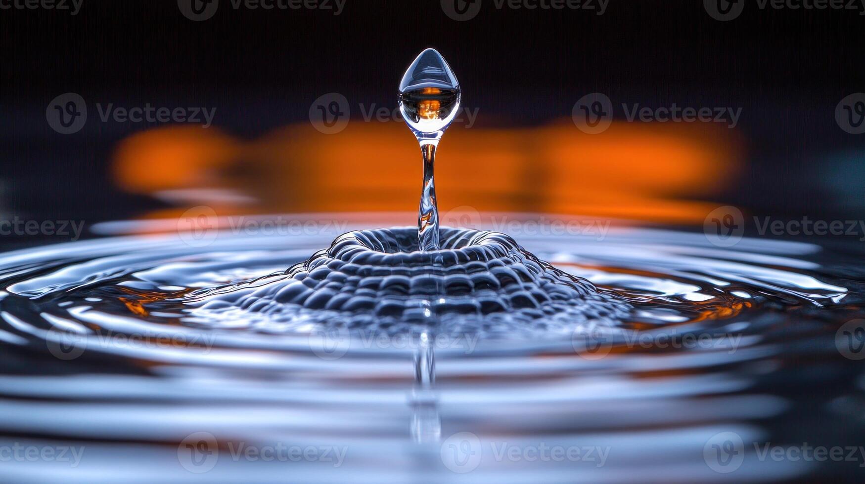 A droplet splashes in calm water, creating mesmerizing ripples in a glowing backdrop photo