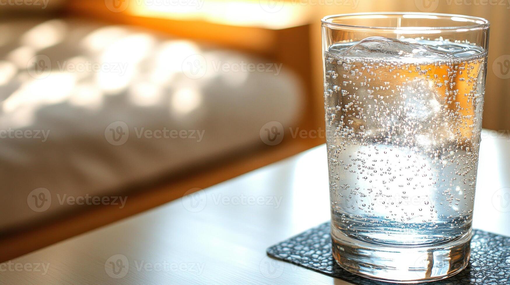A glass of sparkling water on a coaster reflects sunlight, creating a serene vibe photo