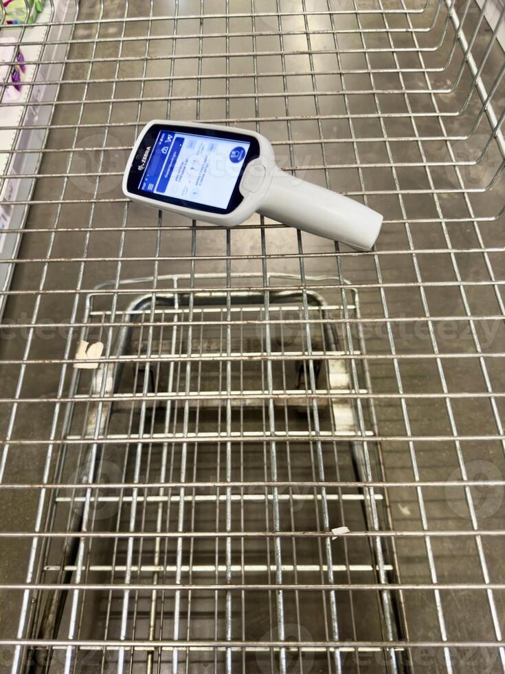 Shopping cart with handheld scanner in a store during a busy day photo