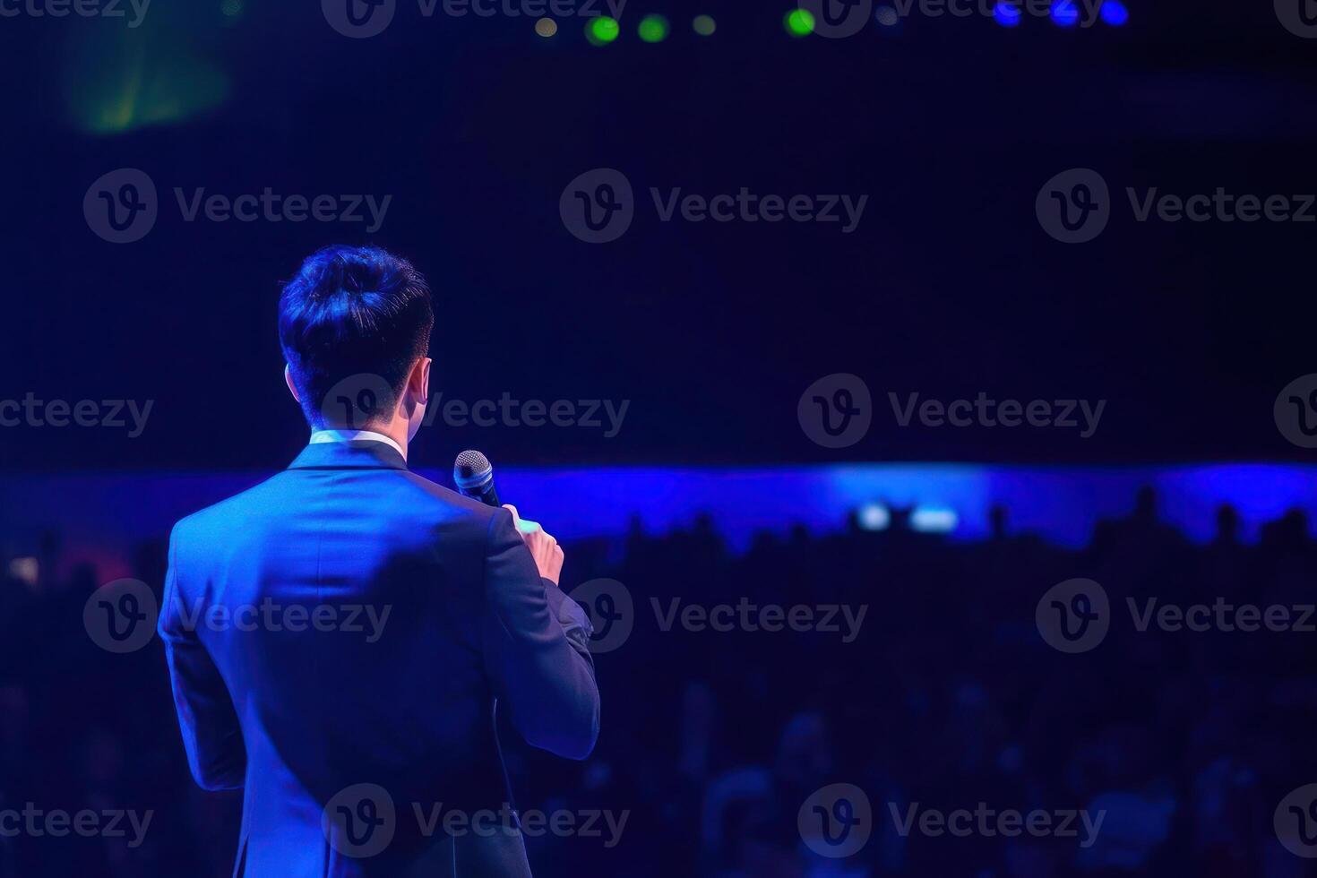 Speaker addressing large audience conference event presentation business meeting microphone man photo
