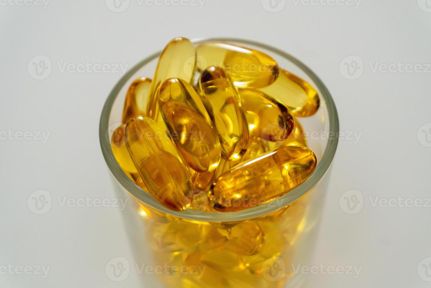 Transparent capsules stacked in a glass container on a neutral background photo