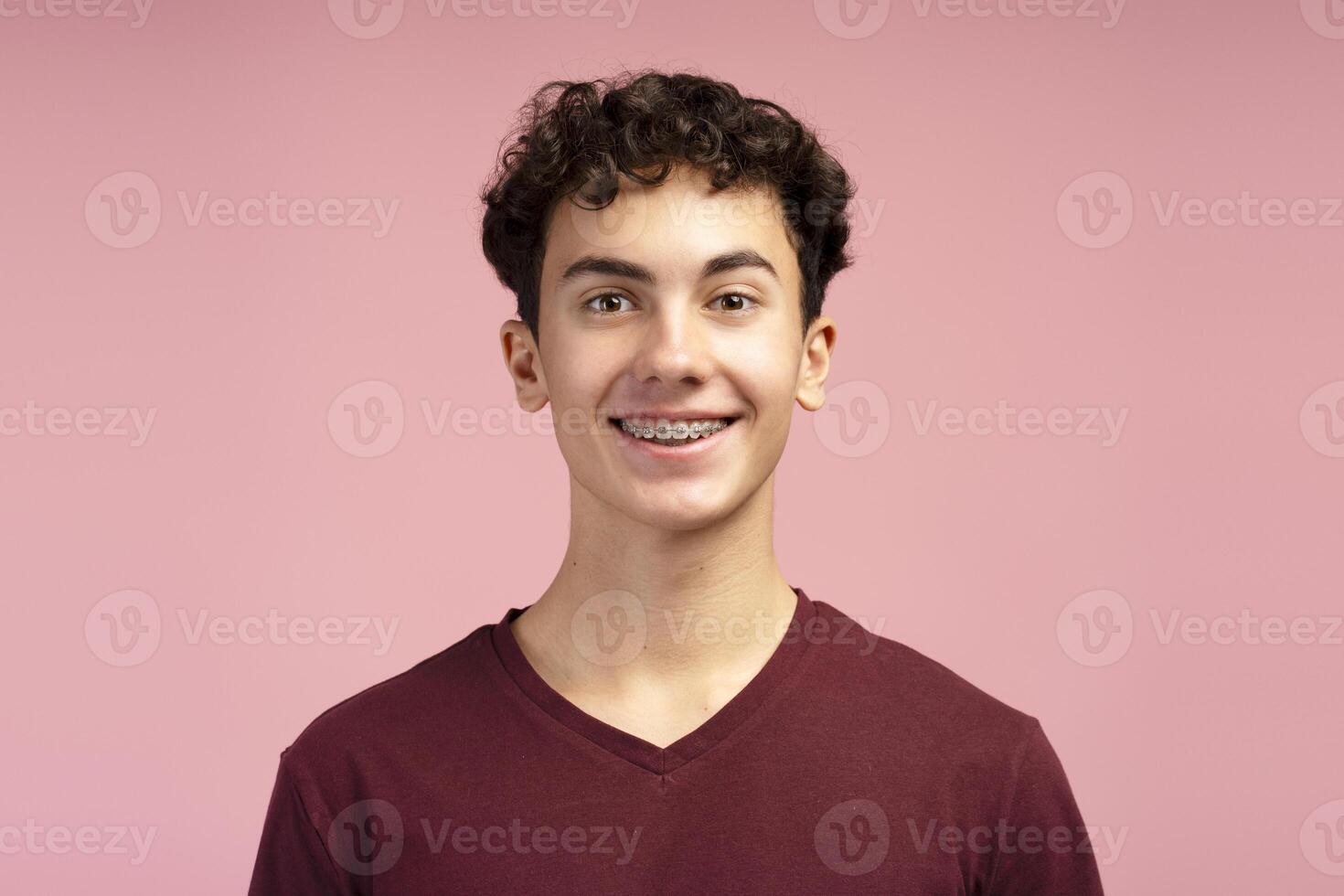 Closeup, portrait of happy, smiling teen boy with braces, posing isolated on pink background photo