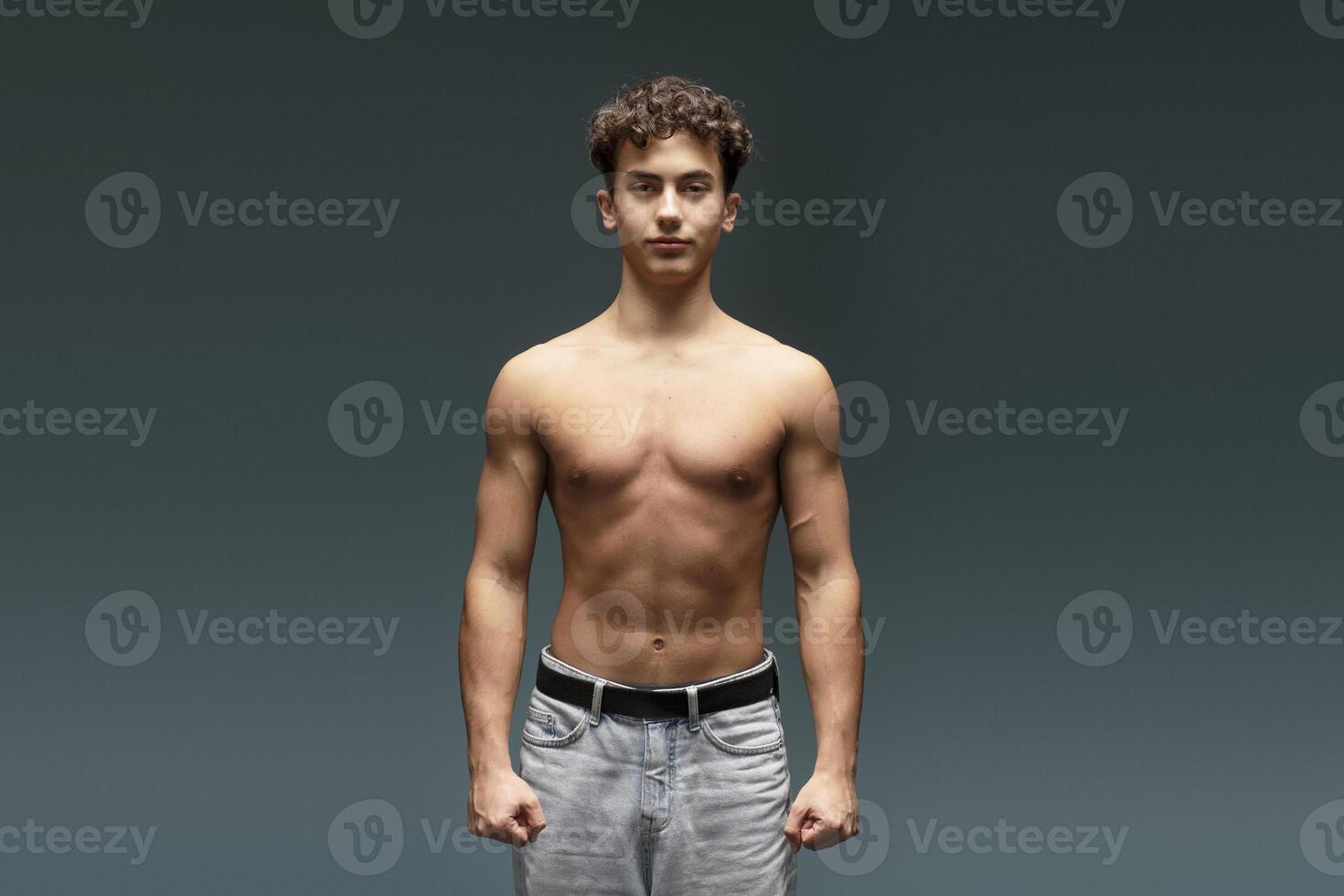 Confident, attractive teen boy with naked torso, bare body, looking at camera, fashion model photo