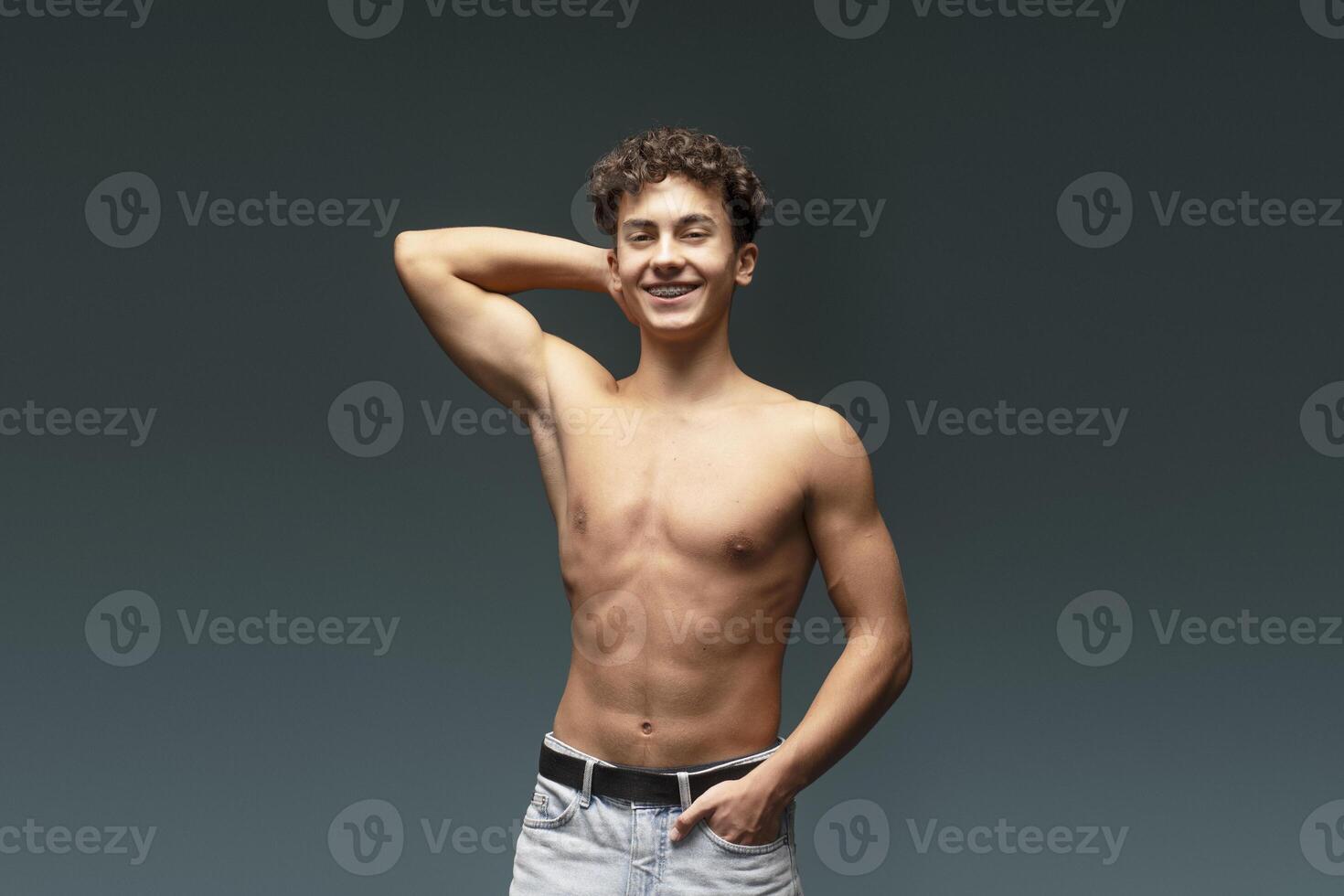 Smiling, attractive with bare torso, muscles body, fashion model posing isolated on gray background photo
