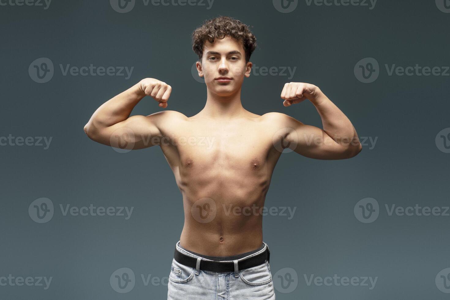 Handsome, attractive, young athlete with bare, muscles torso showing hands with biceps photo