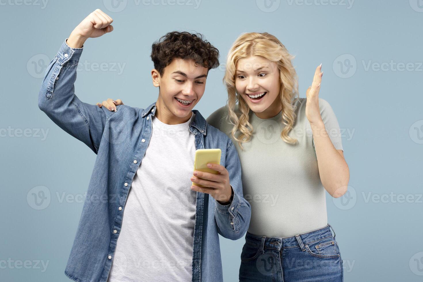 Happy attractive friends, boyfriend and girlfriend holding mobile phone, using mobile app, win money photo