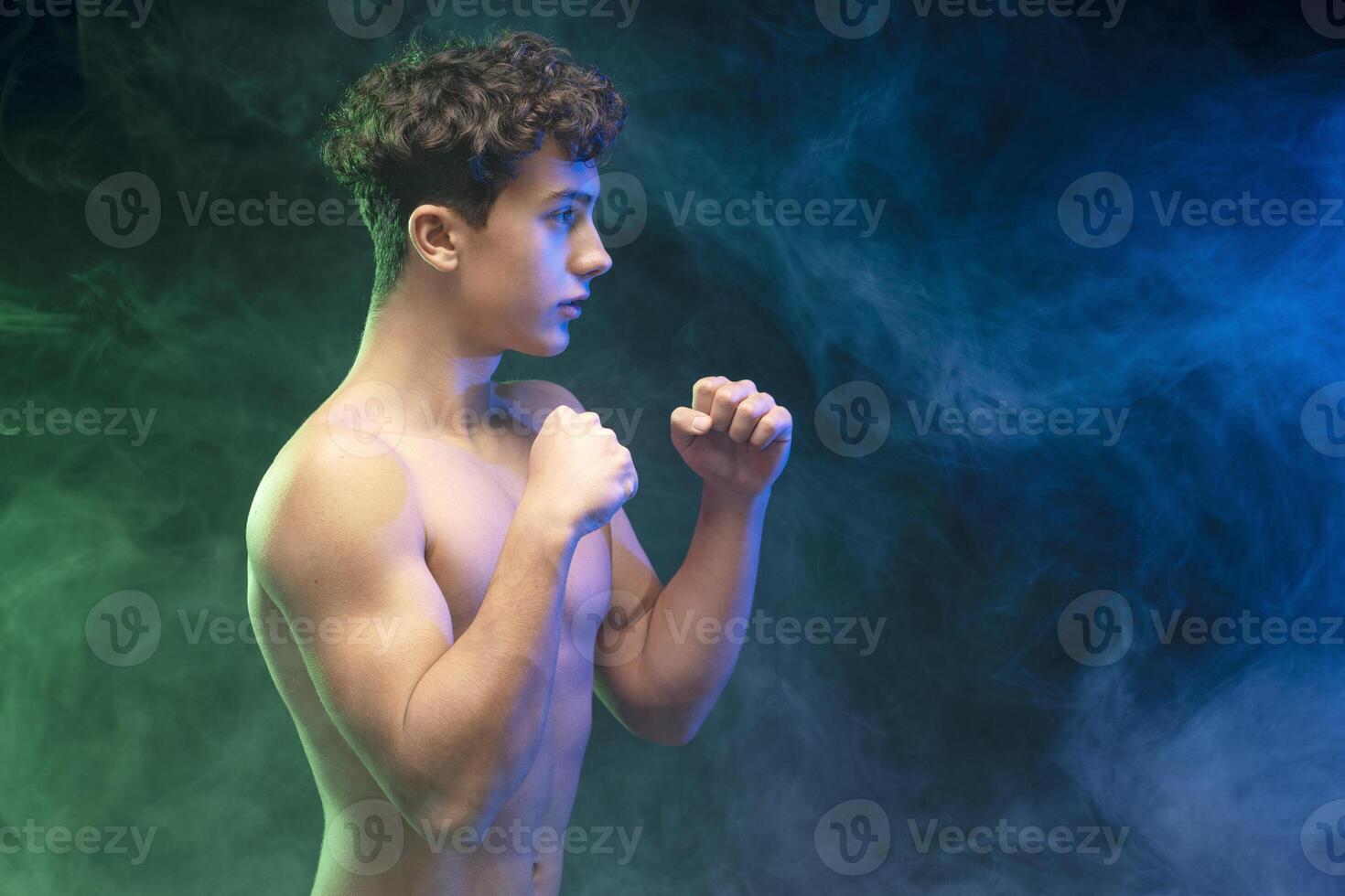 Portrait of pensive serious sportsman, teen boy with bare torso fighting, looking away on copy space photo