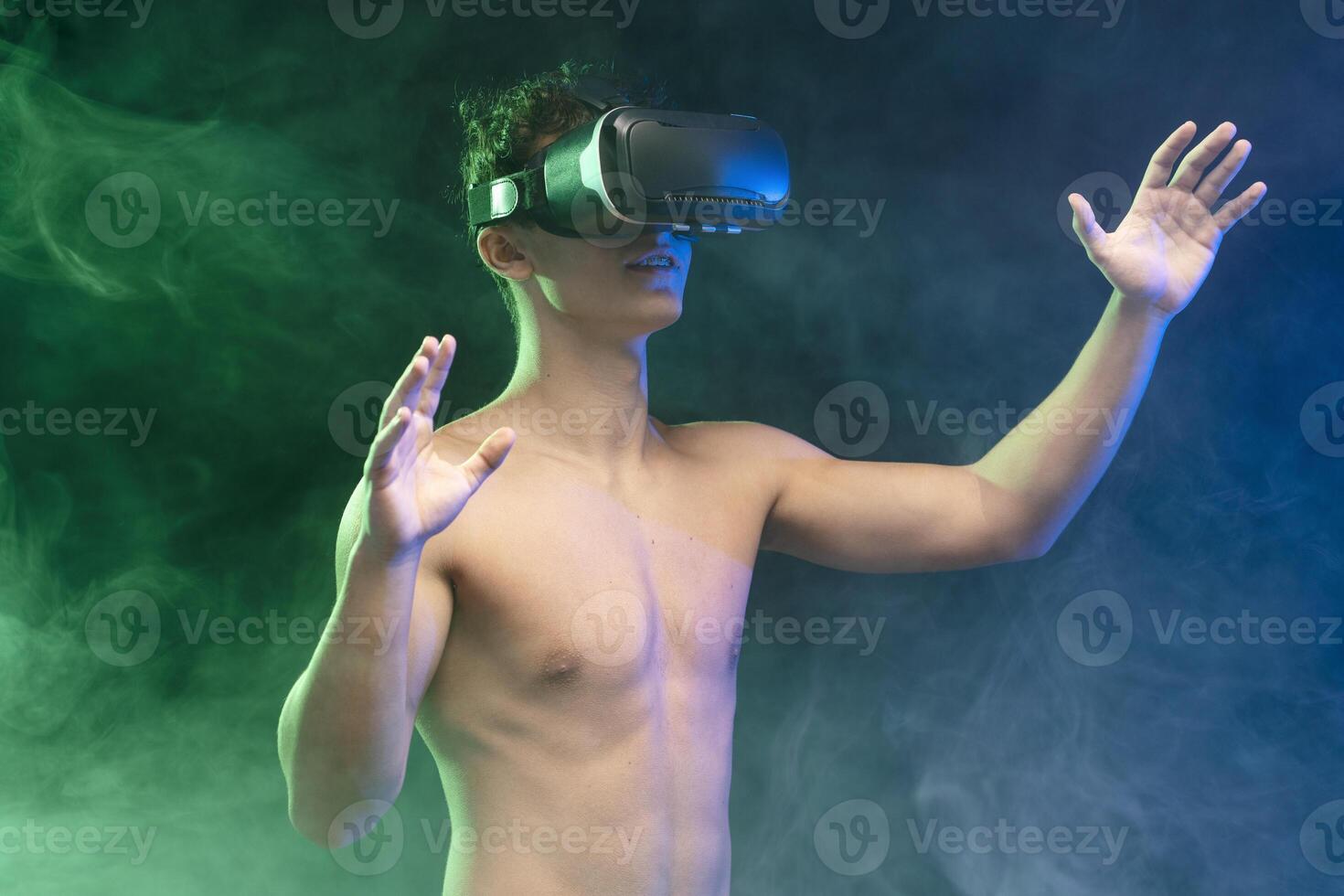 Portrait of young, teenager boy with naked torso wearing VR glasses, playing online game photo