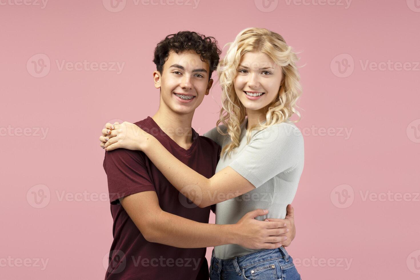 Happy boyfriend and girlfriend, couple embracing together, standing isolated on pink background photo