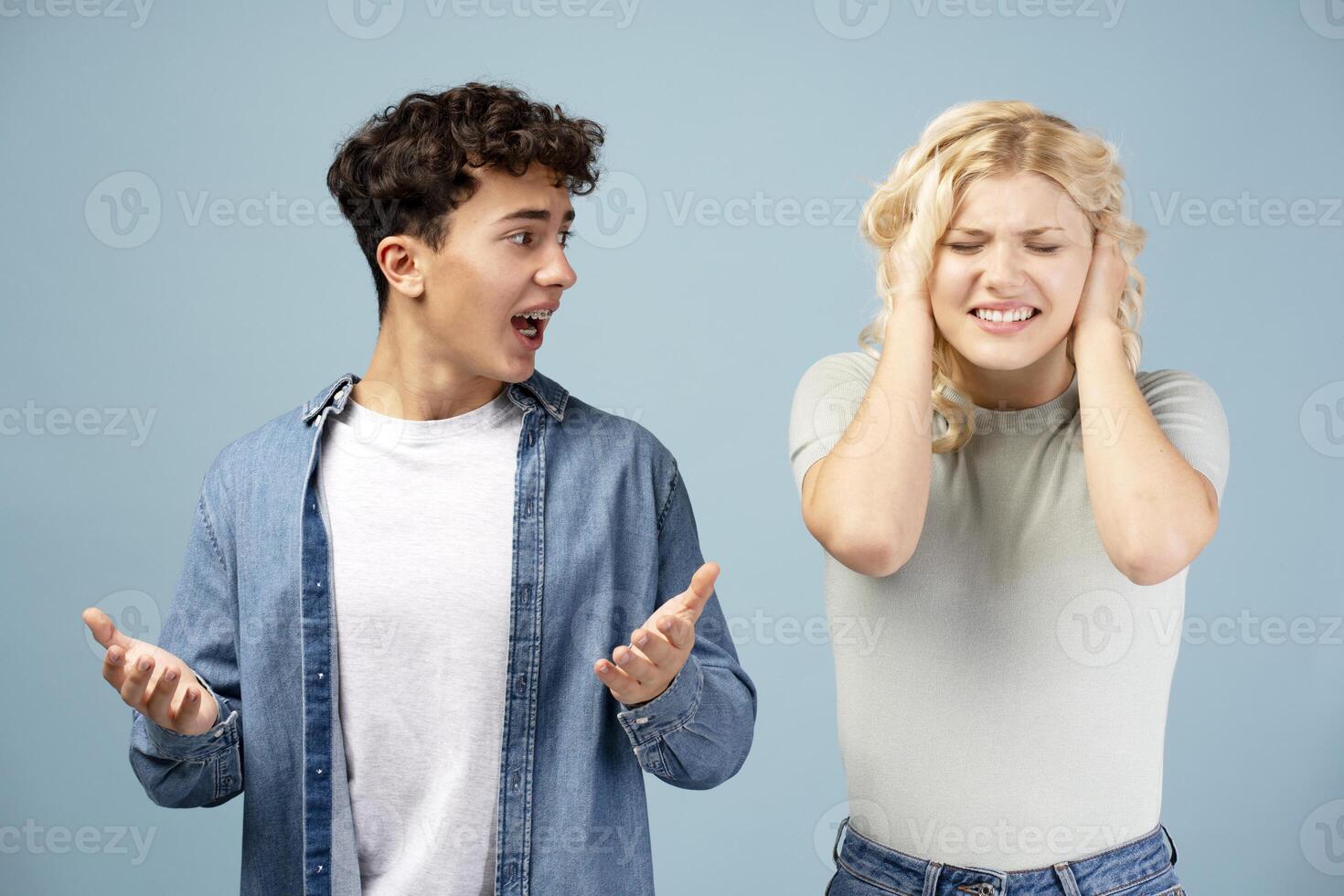 Portrait of angry couple, boyfriend shouting to girlfriend, girl covering ears, having conflict photo