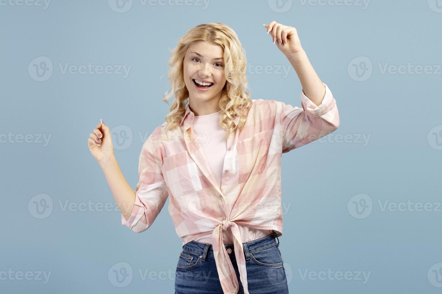 Happy, smiling blonde teenager, beautiful girl wearing casual clothes dancing looking at camera photo
