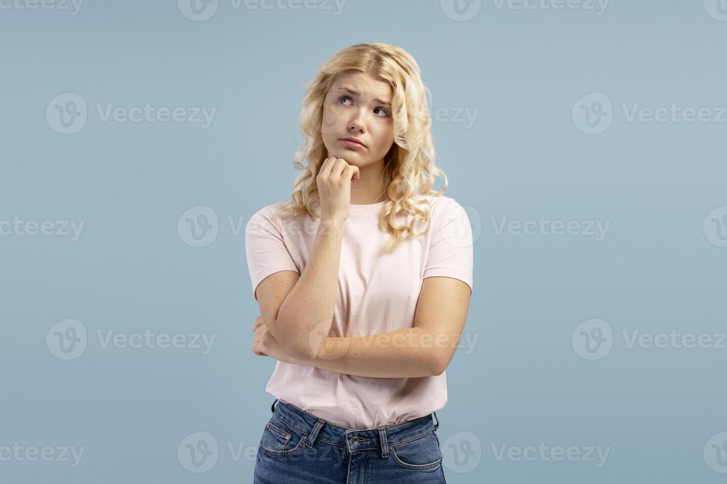 Serious pensive teenager beautiful girl, thinking looking away, standing isolated on blue background photo