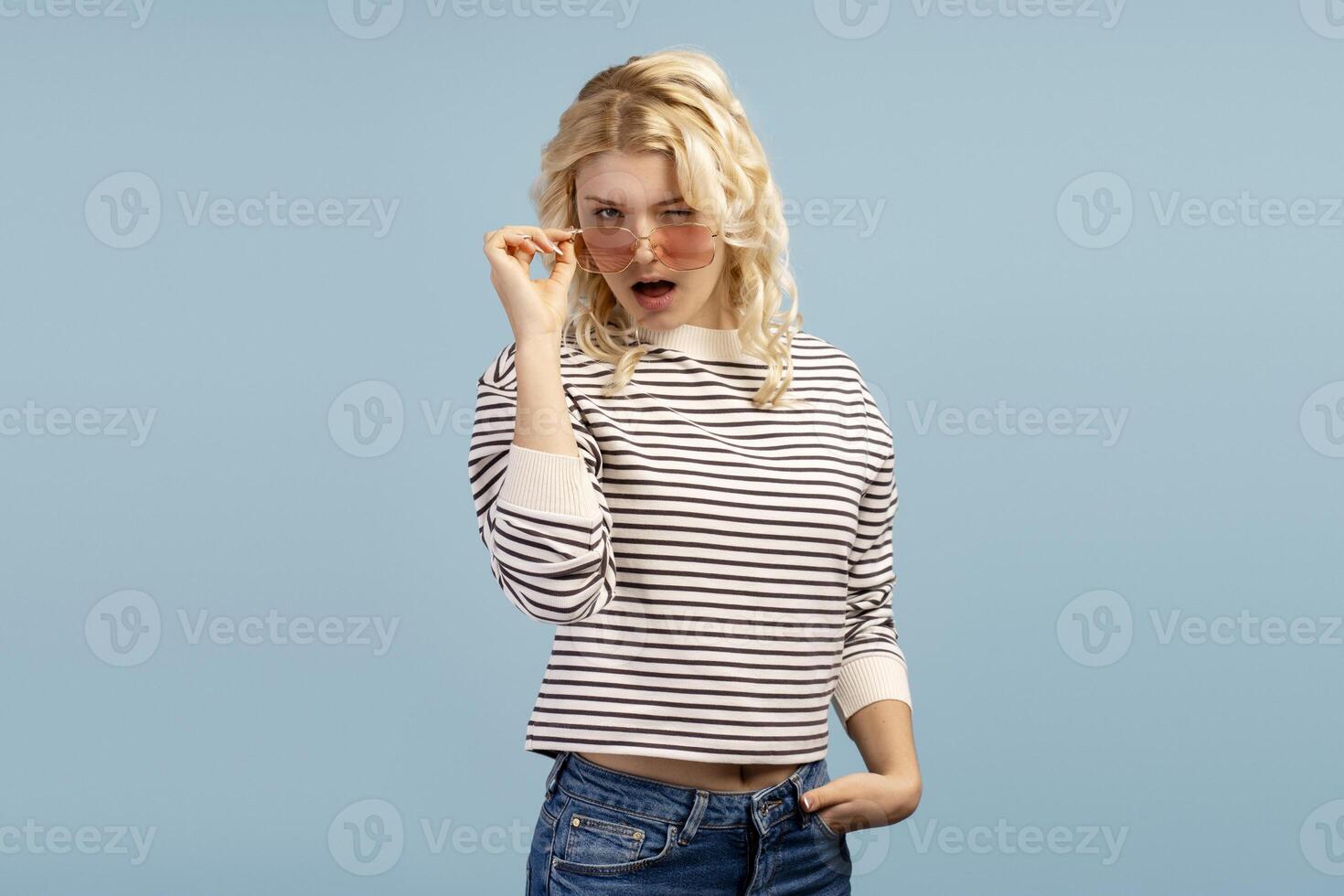 Happy, smiling blonde teenager, fashion model wearing casual sweater and stylish sunglasses photo
