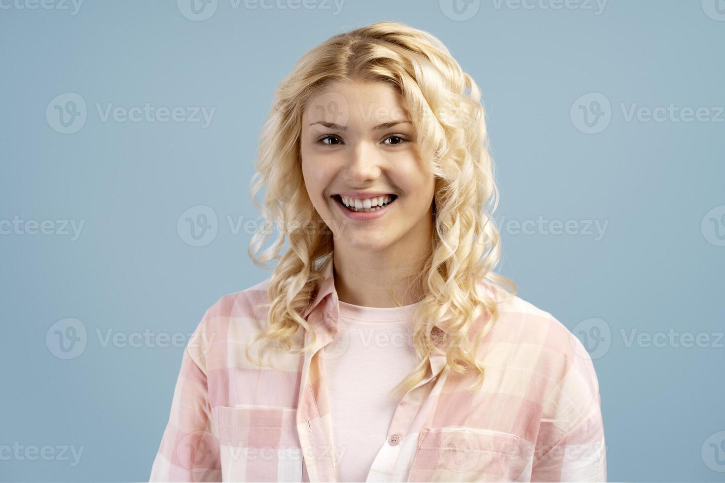Beautiful, young girl wearing casual shirt standing isolated on blue background, looking at camera photo