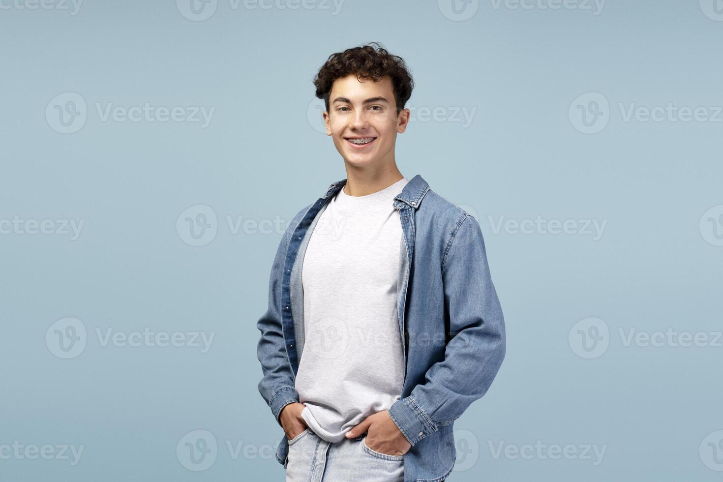 Portrait of happy teenager boy wearing casual clothes, white t shirt and shirt on blue background photo