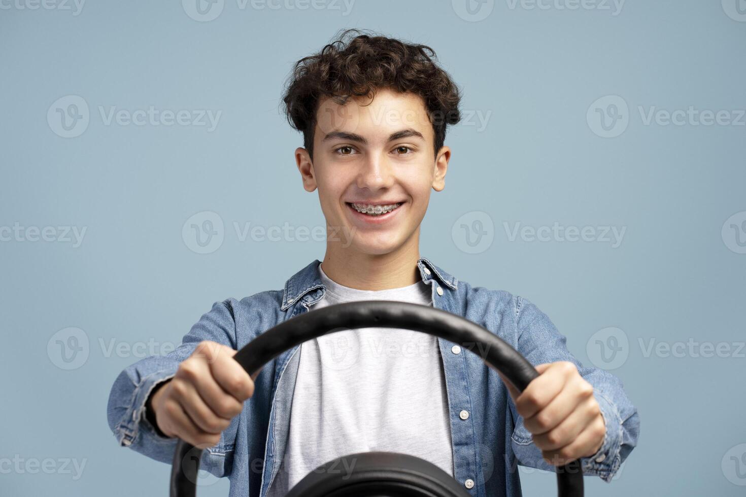 Portrait of smiling handsome teenager boy with braces holding steering wheel. Transportation concept photo