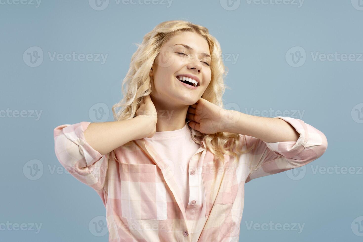 Smiling blonde girl attractive teenager relaxing with closed eyes posing isolated on blue background photo
