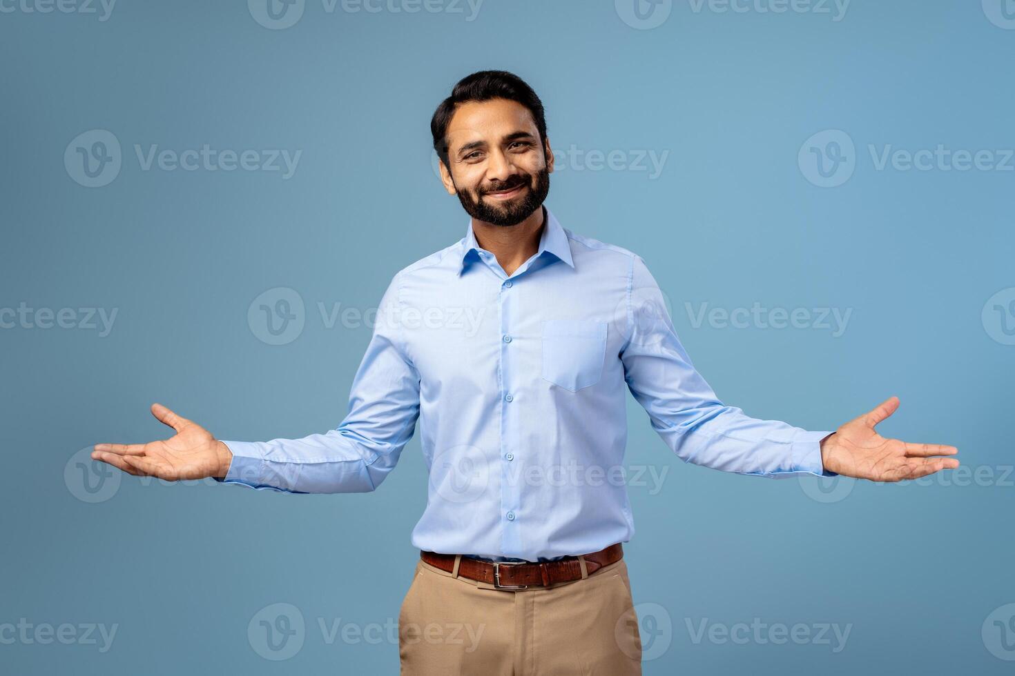 Smiling, positive, handsome Indian bearded man showing hands, looking at camera photo