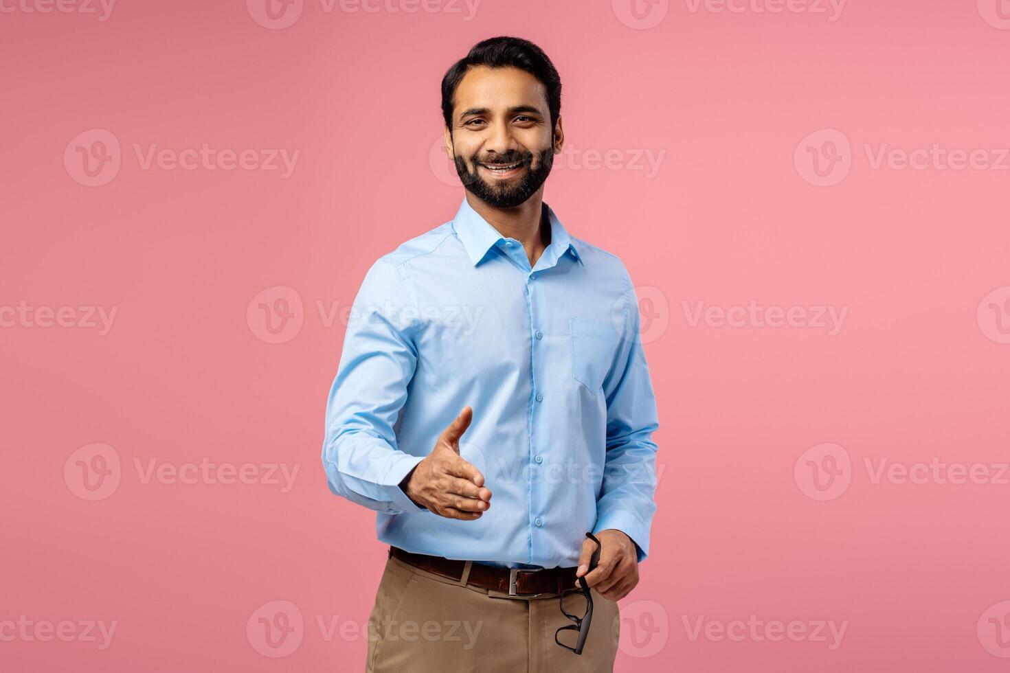 Portrait of smiling, handsome bearded Indian man taking handshake, looking at camera photo