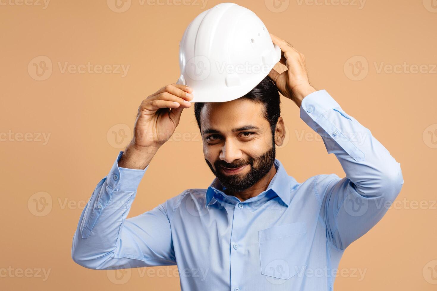 Portrait of smiling, handsome, successful Indian man, businessman wearing white hard hat photo