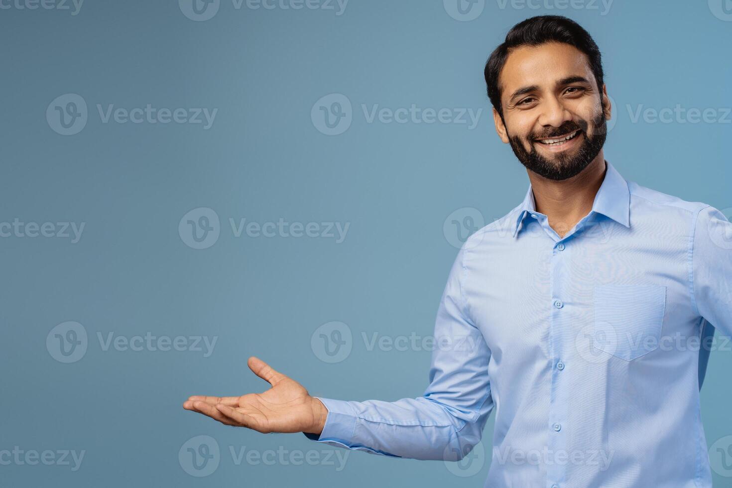 Portrait of smiling, positive, middle aged India man, businessman showing on copy space with hand photo