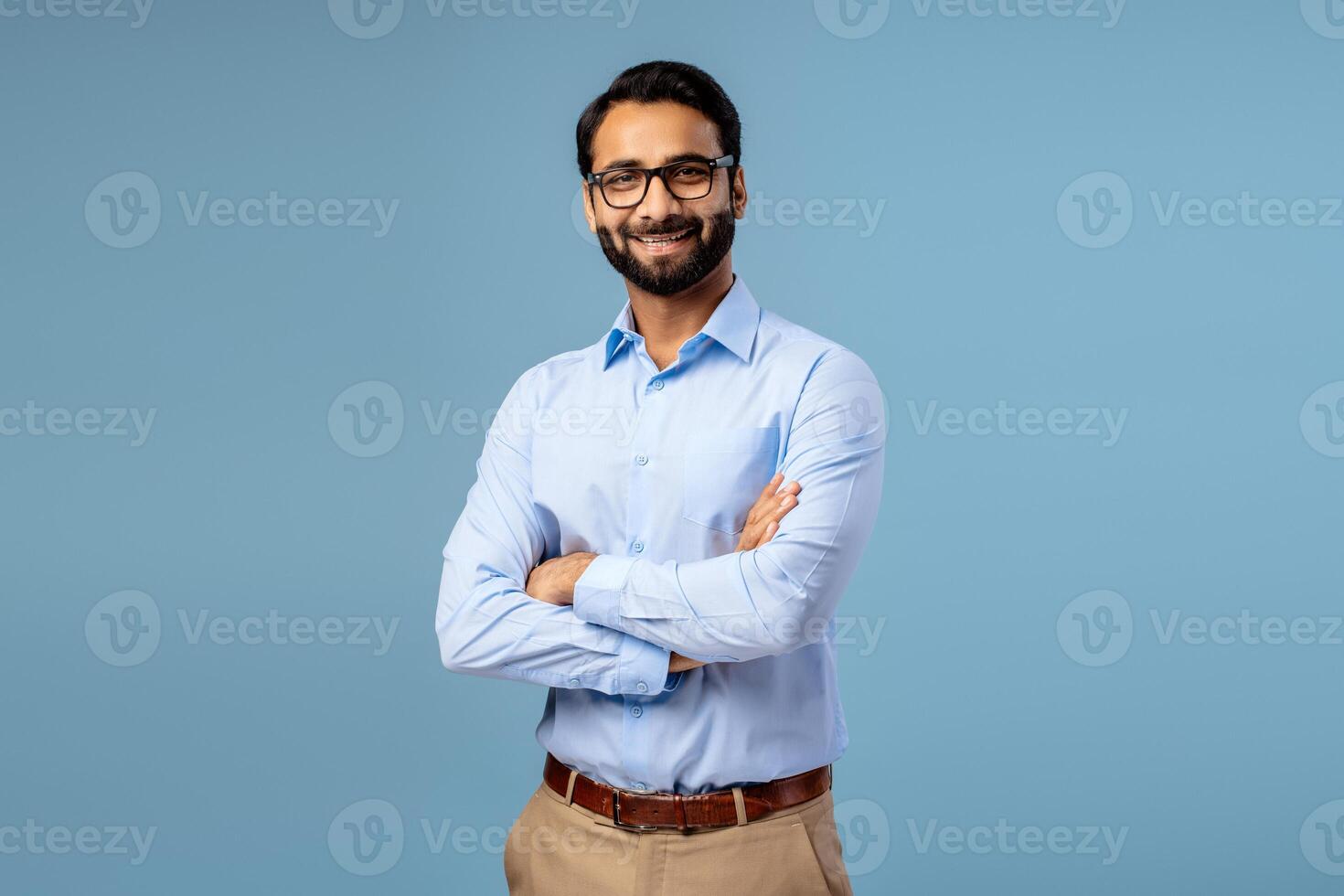Smiling, happy, Indian man wearing casual formal wear with crossed arms wearing stylish eyeglasses photo