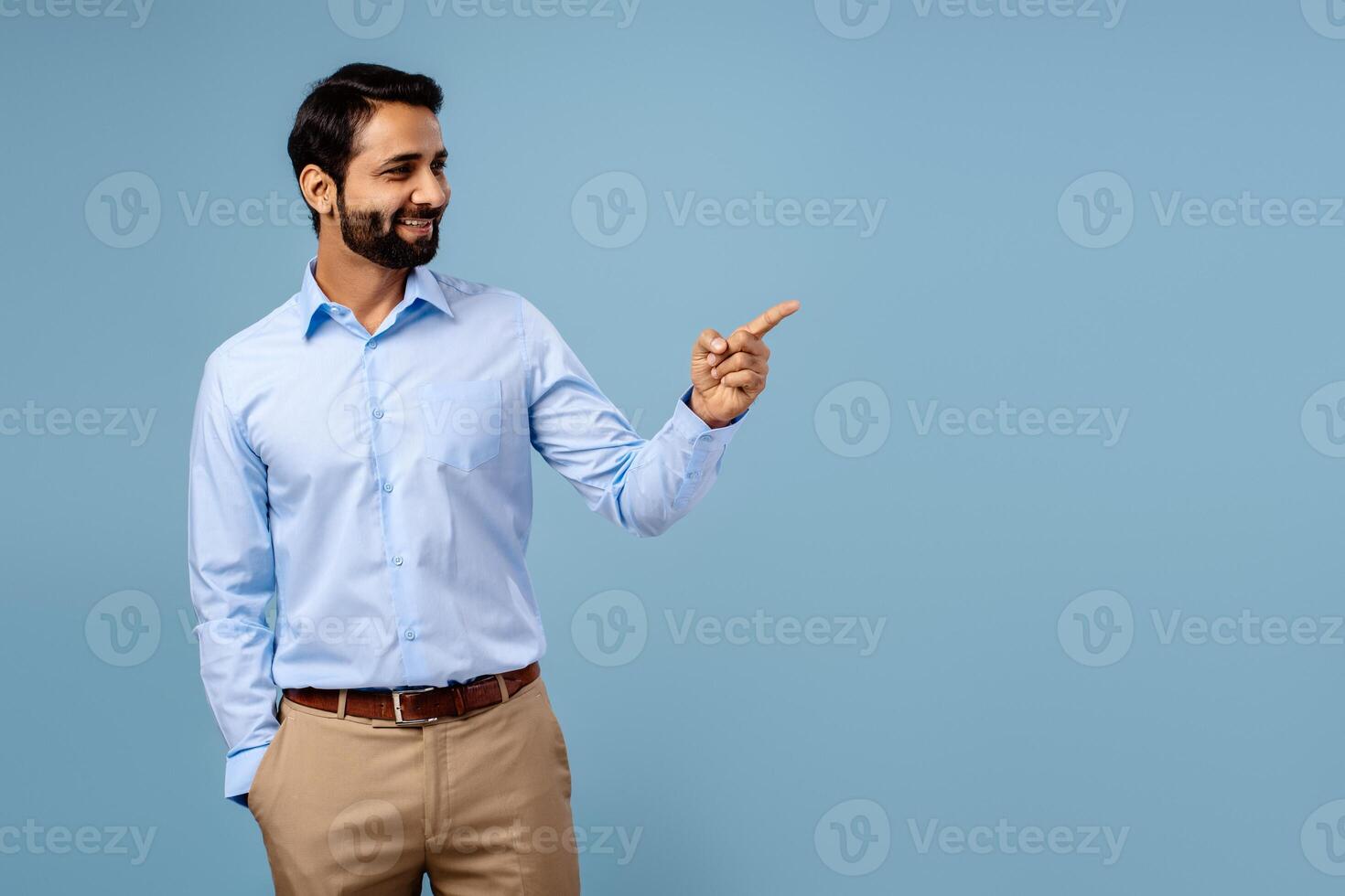 Handsome, attractive, happy bearded man Indian businessman pointing finger on copy space photo