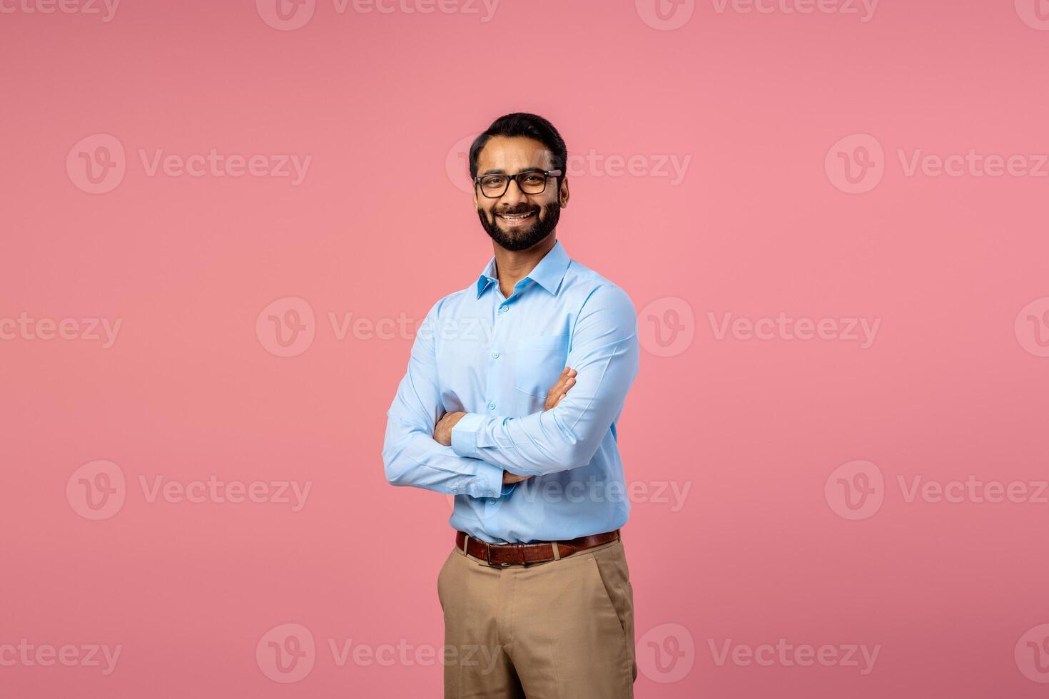Confident successful Indian bearded man wearing formal wear and stylish eyeglasses with crossed arms photo
