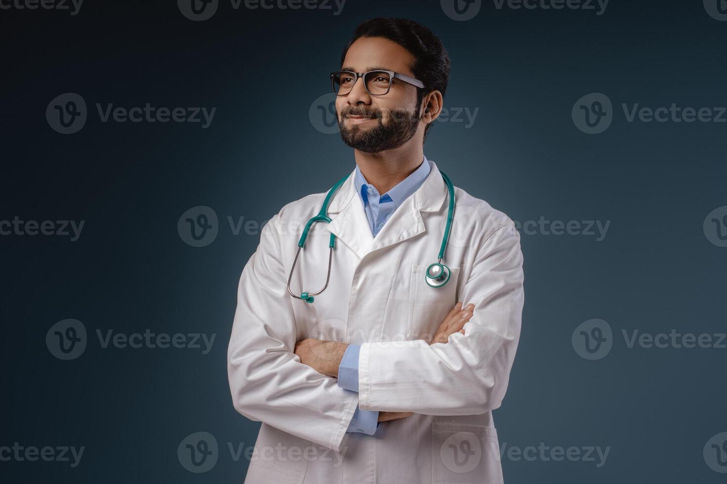 Smiling Indian man, doctor wearing stylish eyeglasses, white coat with crossed arms looking away photo