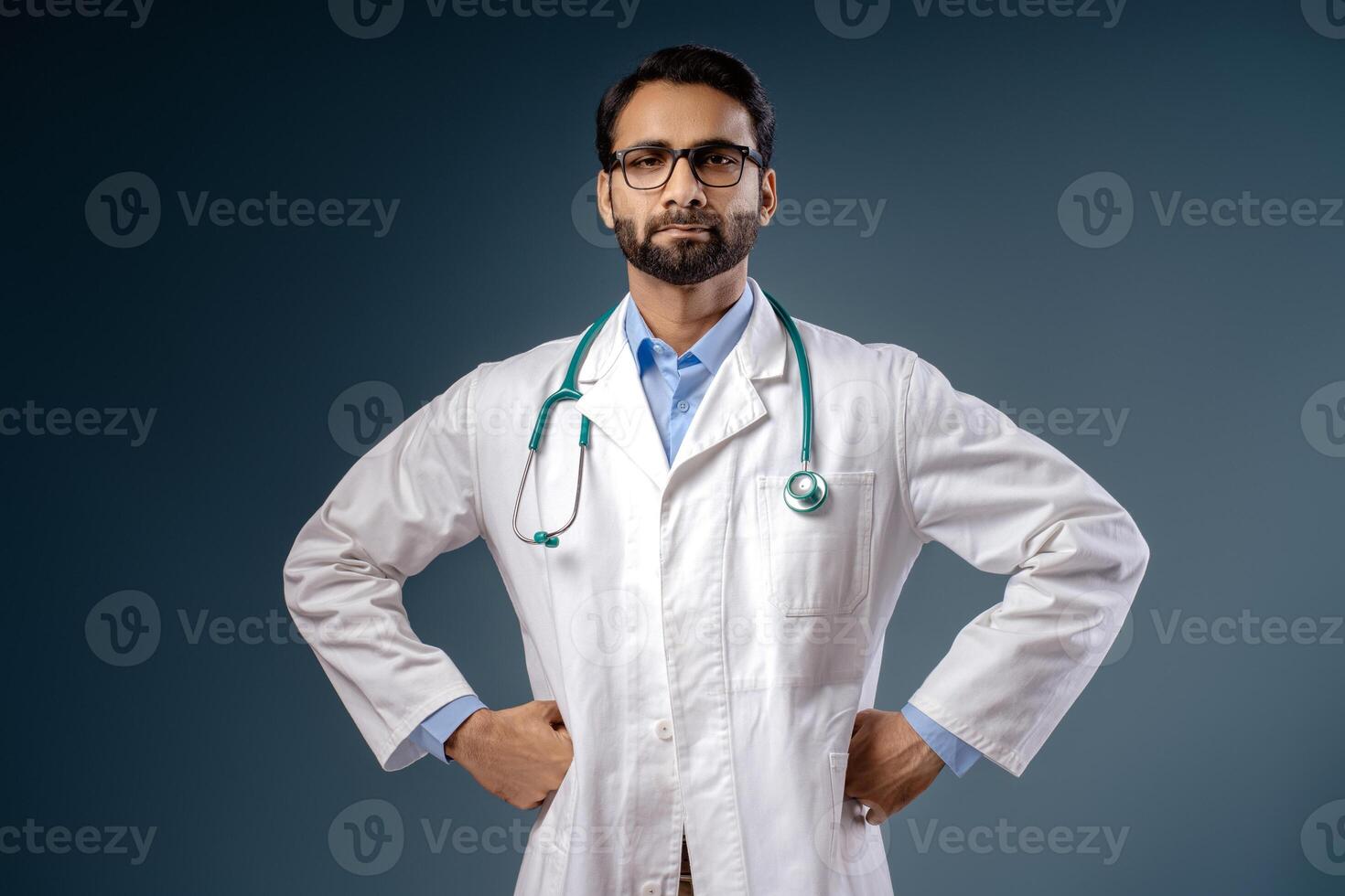Portrait of serious, pensive Indian doctor wearing white coat stylish eyeglasses, looking at camera photo