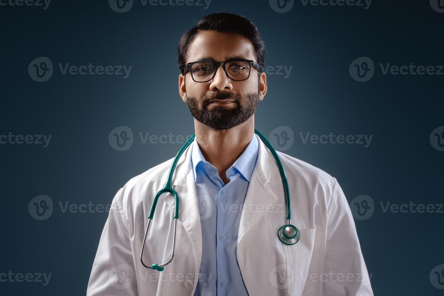 Portrait of serious, pensive bearded, professional Indian man wearing white coat, stylish eyeglasses photo