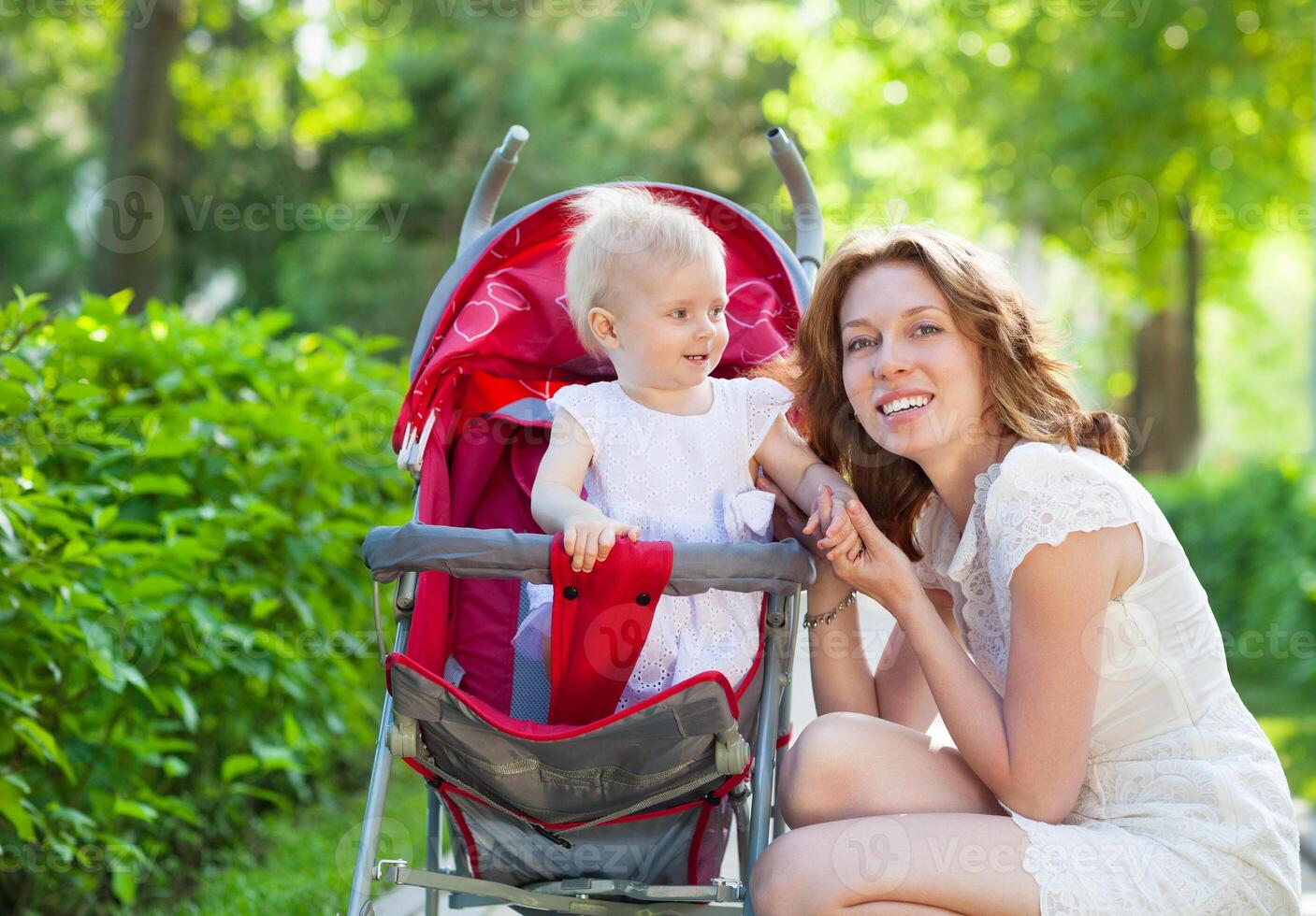 Beautiful young woman with her child in a baby carriage photo
