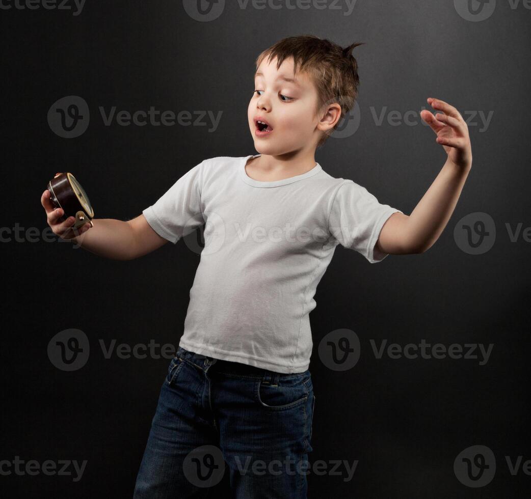 Funny little boy looking at alarm clock photo