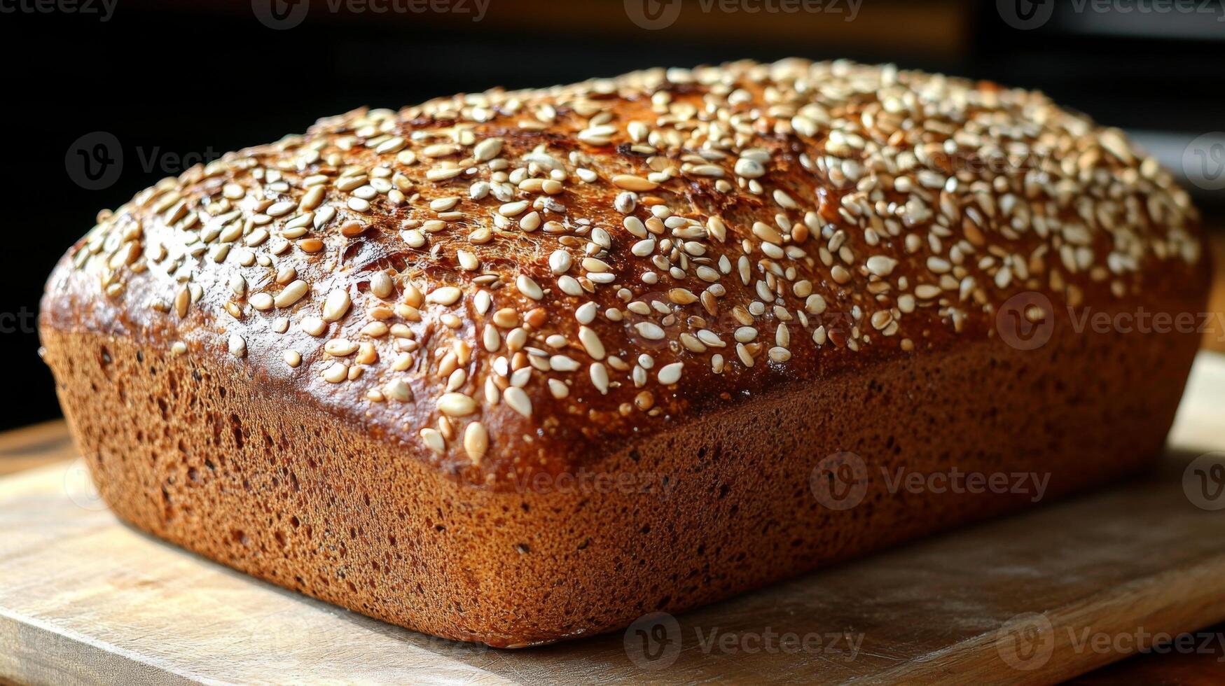 A loaf of freshly baked whole grain bread, rich in texture and flavor, is topped with sesame seeds and rests on a wooden cutting board, inviting enjoyment. photo