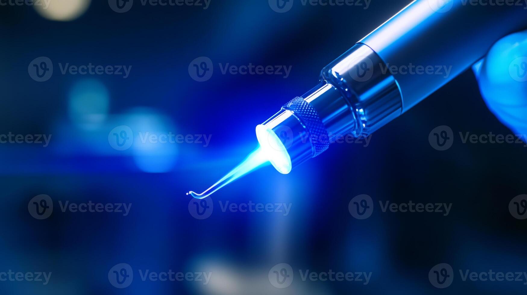 A dental professional prepares to utilize advanced laser technology in a clinical setting. The tool emits a focused blue light, emphasizing precision and innovation in dental treatments. photo
