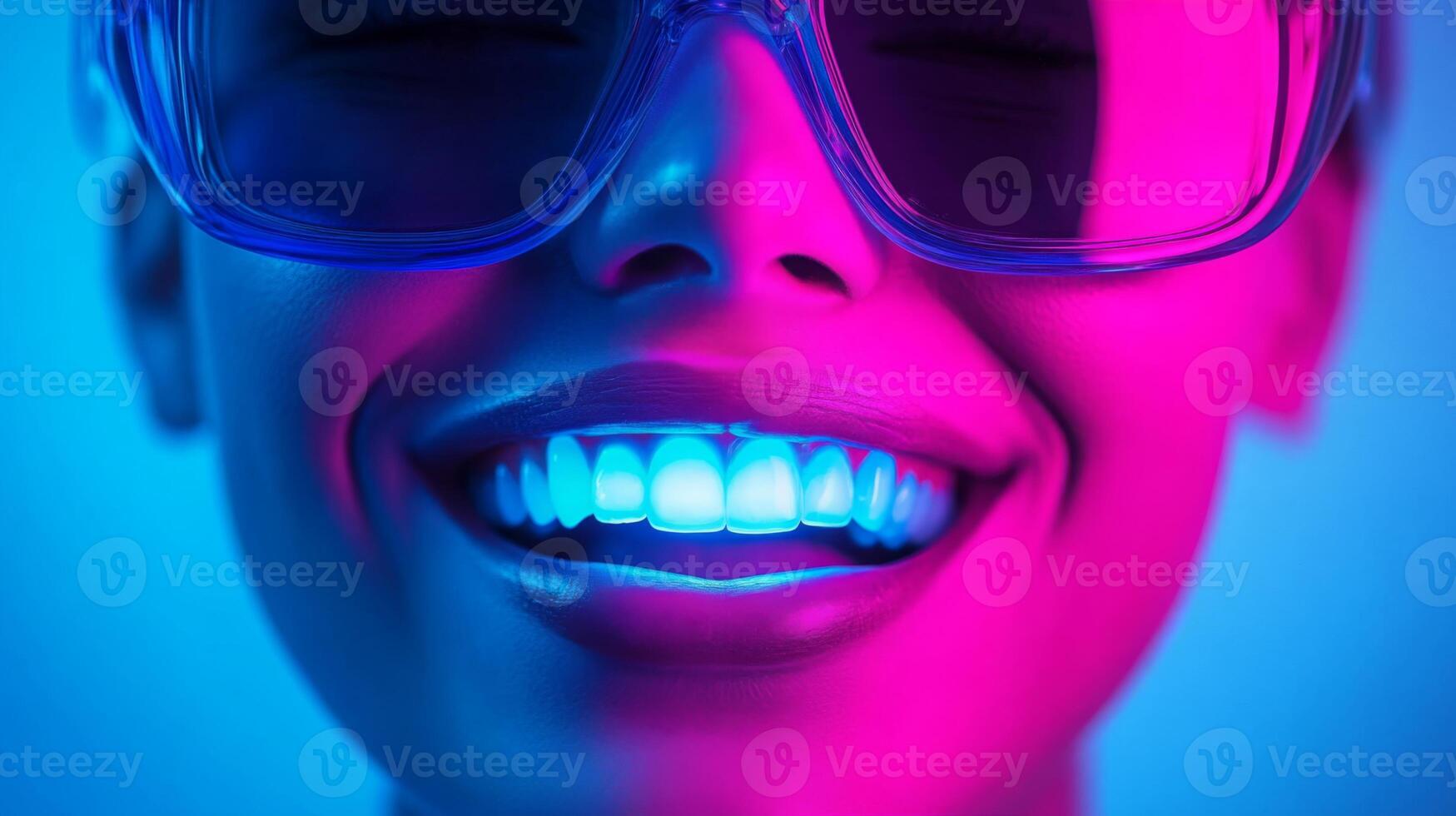 A person with a radiant smile displays perfectly white teeth, illuminated by vibrant blue and pink lighting. They are wearing protective eyewear, indicating a focus on advanced dental treatment. photo
