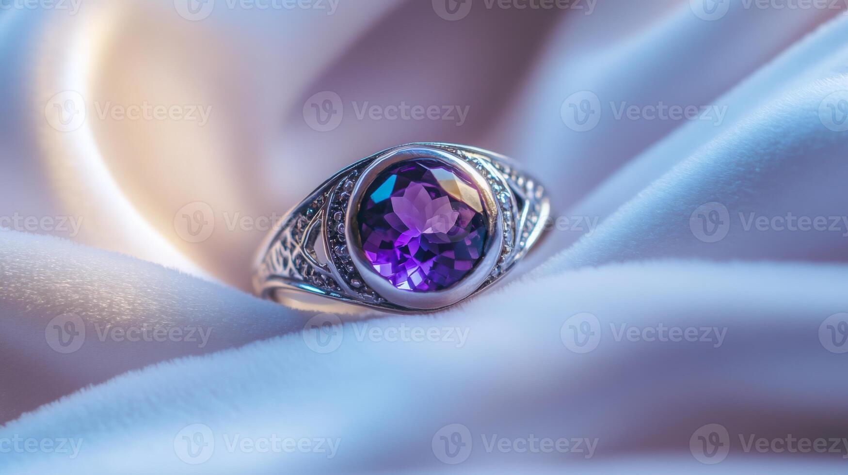 A silver ring with an intricate design showcases a stunning purple gemstone at its center. The ring is delicately placed on soft, silky fabric, enhancing its elegance and charm. photo