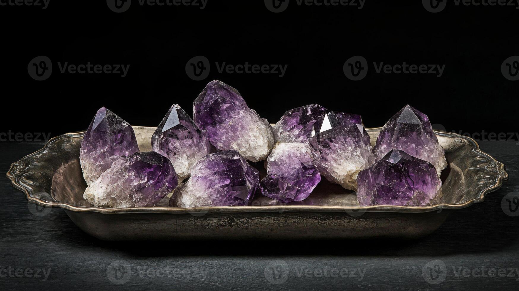 Intricate amethyst gemstones are arranged on a vintage silver tray, showcasing their rich purple hues and stunning clarity. The setting highlights the natural beauty and shine of each stone. photo