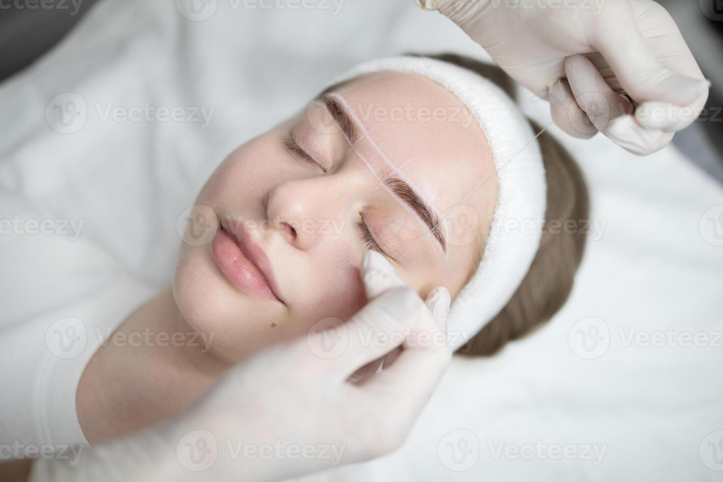 Two woman are engaged in a pampering beauty session at a salon, focusing on a permanent makeup procedure. One woman is applying makeup while the other relaxes during the treatment. photo