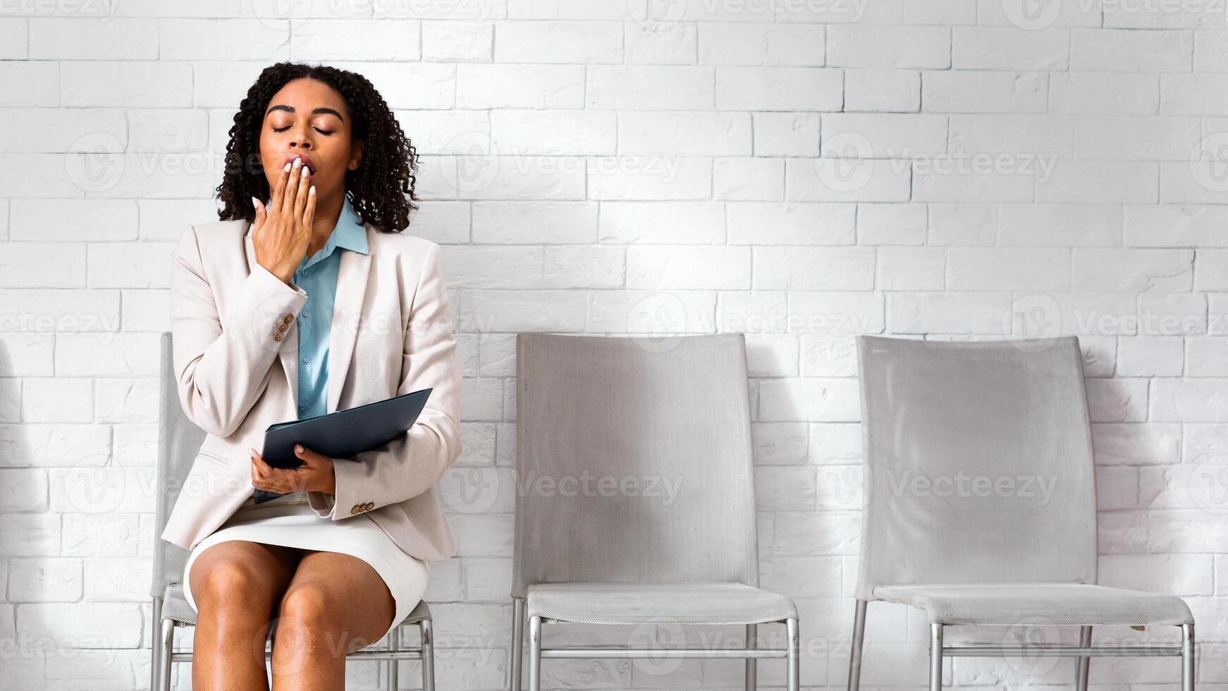 Millennial woman yawning, tired from waiting for her job interview in corporate office. Free space photo