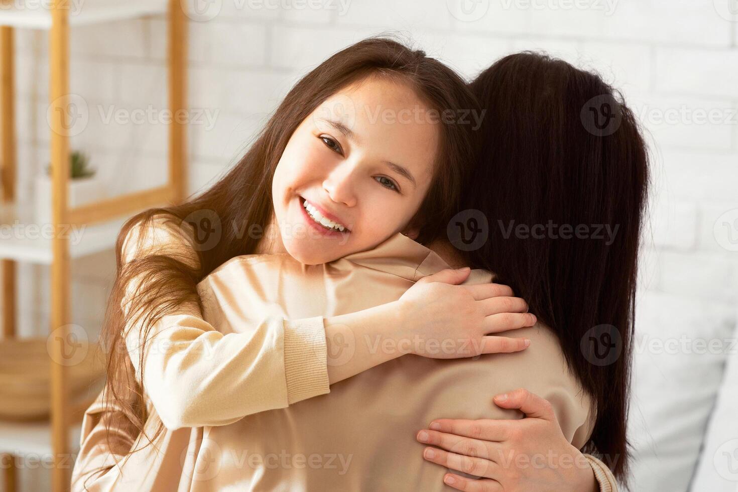 Affectionate family times. Charming teen girl and her mom emracing at home photo