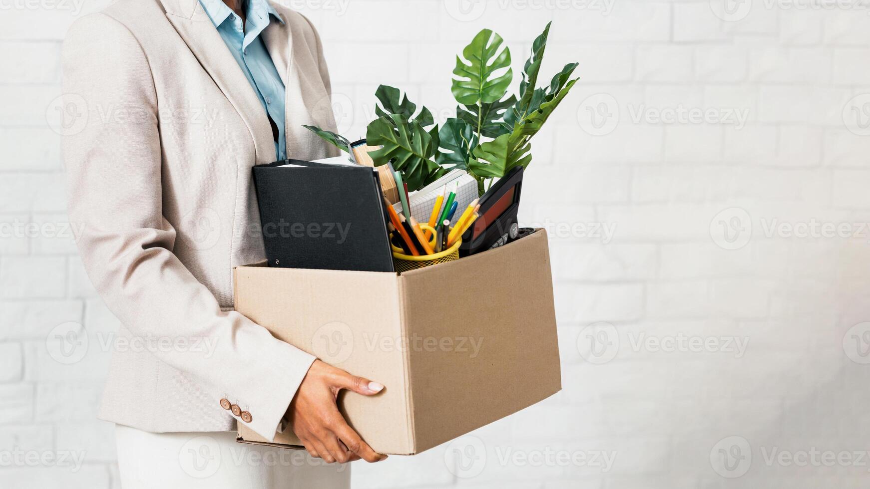 Unrecognizable black woman holding box of personal belongings, leaving office after losing her job, closeup of hands. Economic crisis and unemployment during covid-19 epidemic photo
