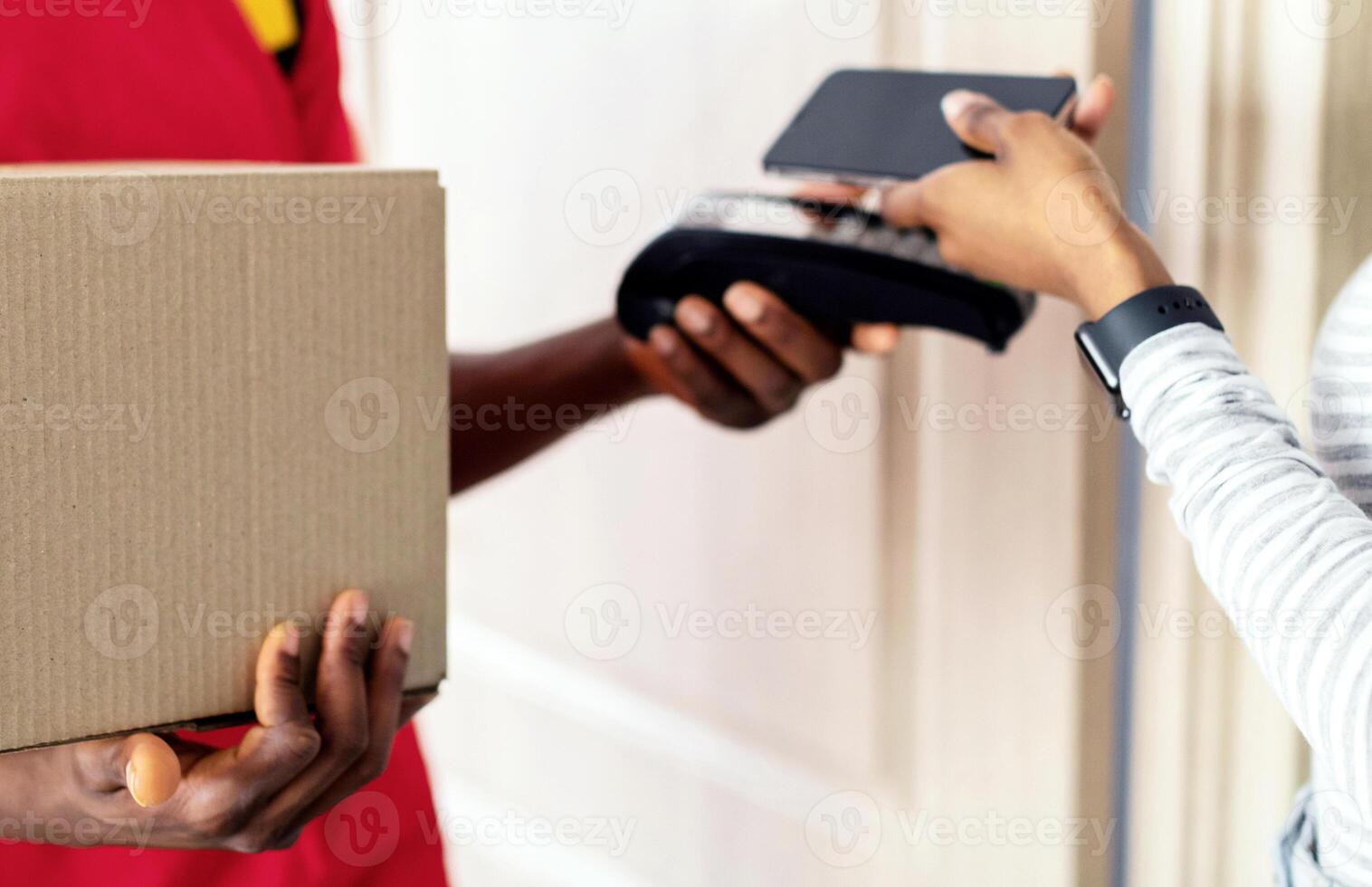 Customer Paying Courier For Delivery Using Smartphone, Receiving Parcel Box At Home. Closeup Of Black Lady Putting Phone To Payment Terminal In Doorway Of Her Home. Mobile Banking Concept. Cropped photo