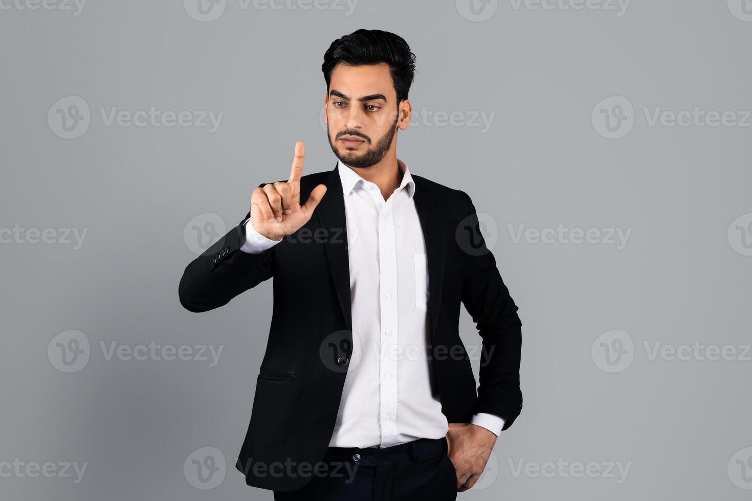 A Middle Eastern businessman stands in a well-lit studio, making a hand gesture that conveys authority. Dressed in a sleek suit, he exudes confidence and professionalism in a corporate lifestyle. photo